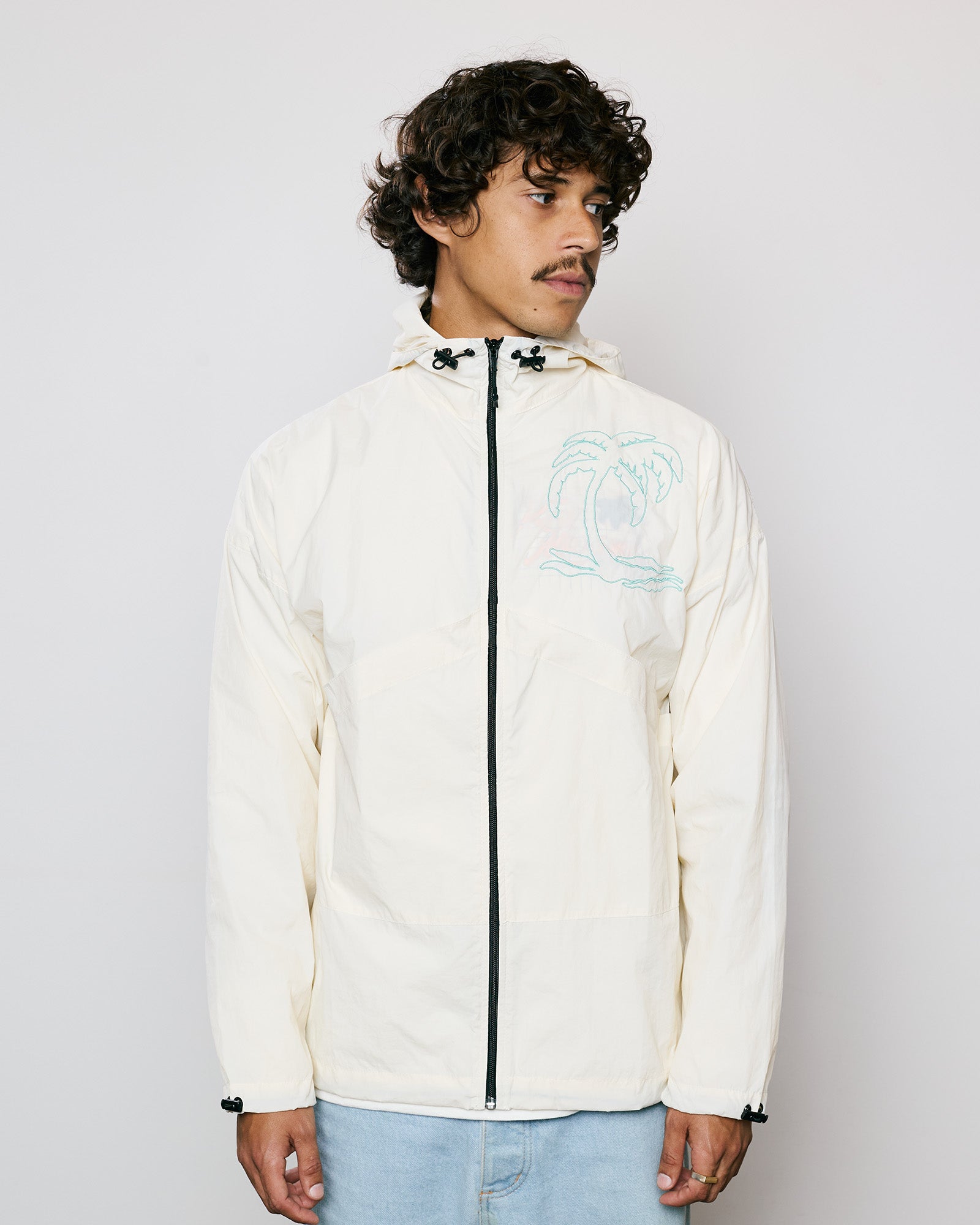 Jaqueta Wind Kiji x Maxime Palm Tree em off-white, com capuz e bolsos, ideal para dias leves.