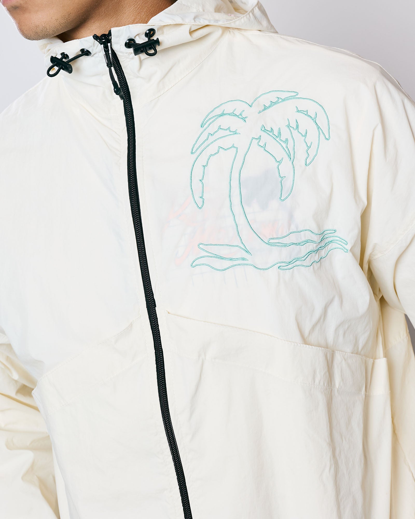 Jaqueta Wind Kiji x Maxime Off White com estampa de palmeira e capuz ajustável, leve e respirável.