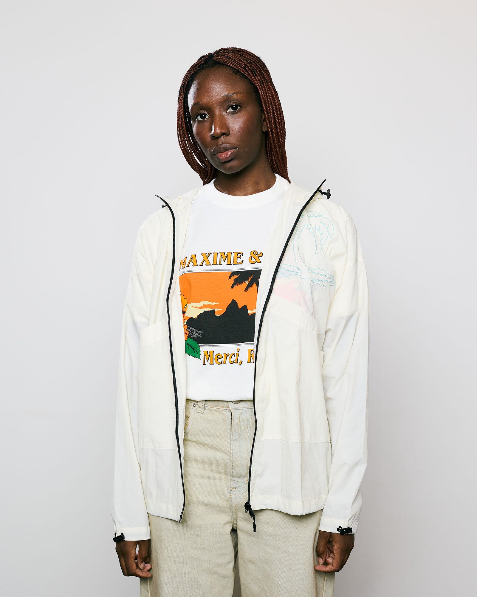 Modelo vestindo a Jaqueta Wind Kiji x Maxime Palm Tree na cor Off White, com capuz e bolsos frontais.