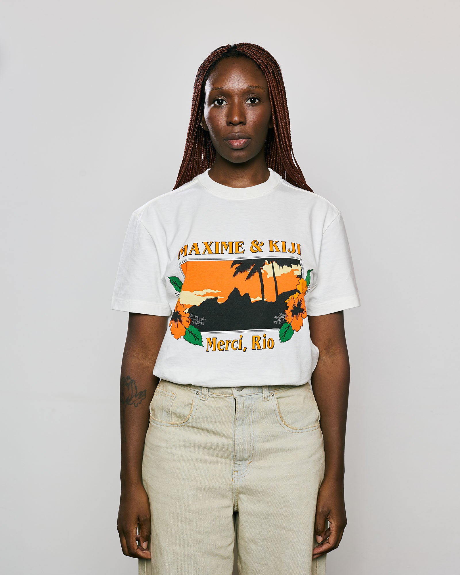 Modelo vestindo a T-Shirt Classic Kiji x Maxime Merci Rio na cor Off White, com design tropical e cores vibrantes.