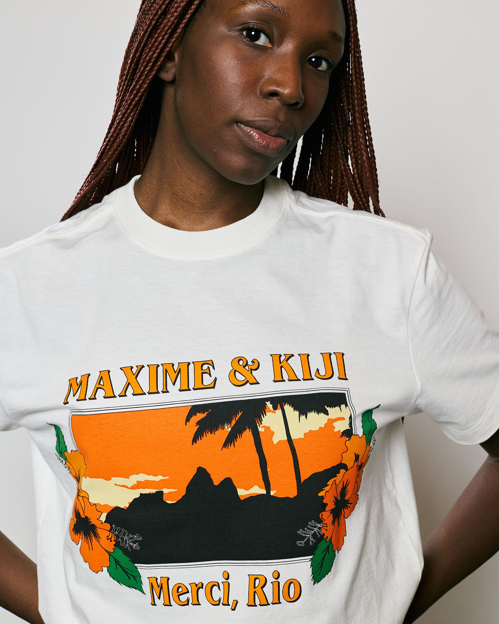 Modelo usando camiseta Off White Maxime & Kiji com estampa vibrante de pôr do sol e elementos florais.