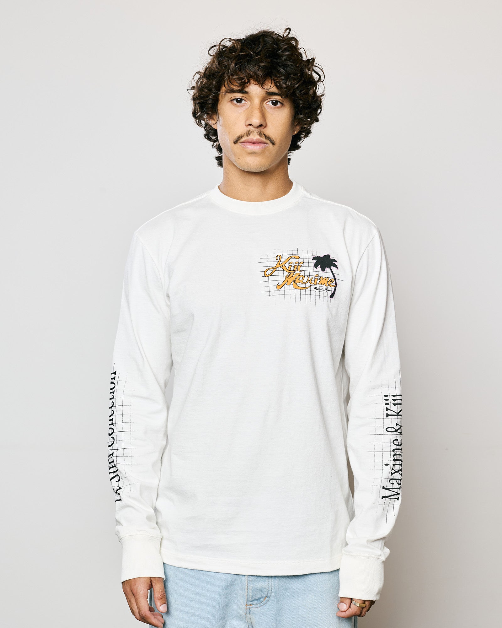 Modelo vestindo a T-Shirt Classic Manga Longa Kiji x Maxime S.L.B. na cor Off White, com caimento casual e estampa exclusiva.
