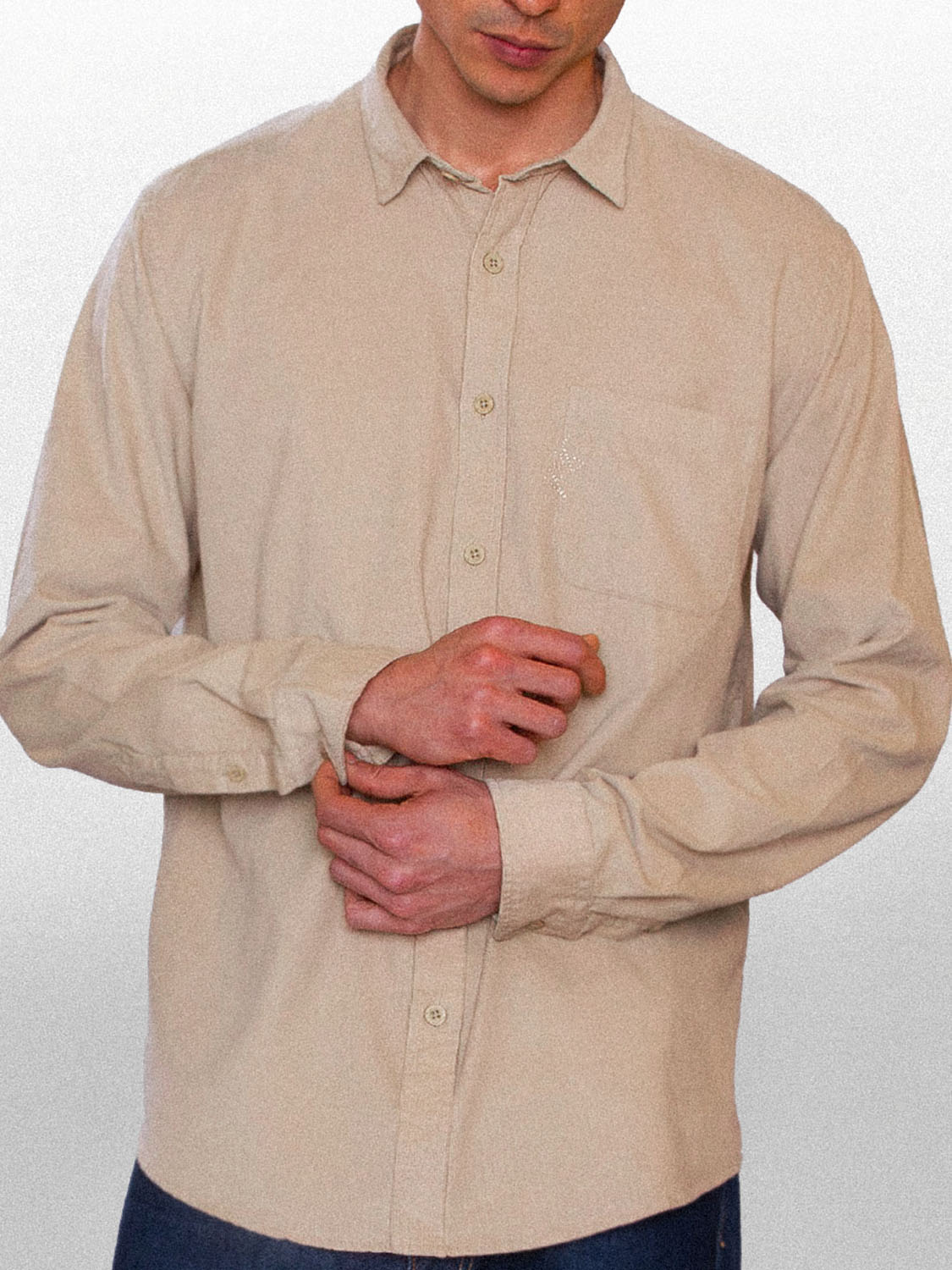 Modelo de frente ajustando o botão da manga, vestido a camisa de botão unique kiji velvet, na cor creme.