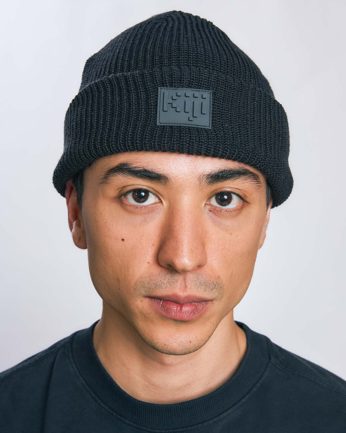 Modelo vestindo Gorro 8bit Kiji de frente, com patch frontal centralizado, na cor preto.