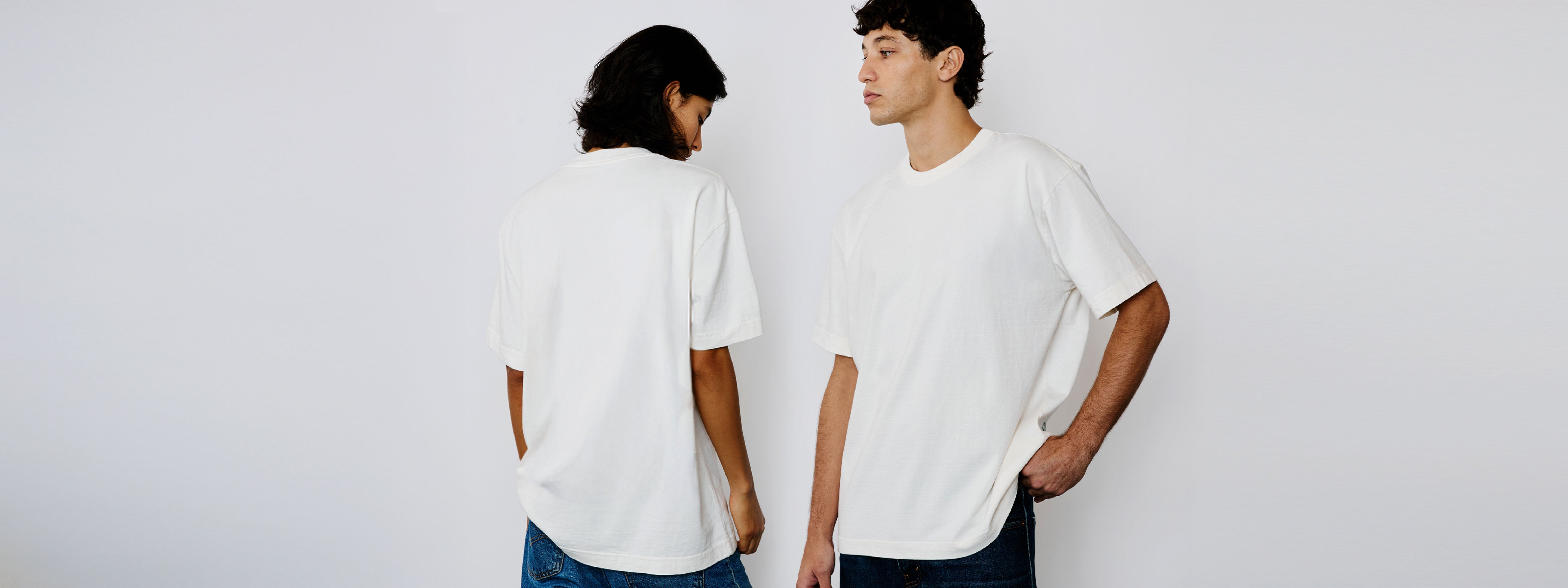 Modelo feminino e modelo masculino vestindo a camiseta heavy oversized off white Kiji, em foto ampla ela de costas e ele de frente.