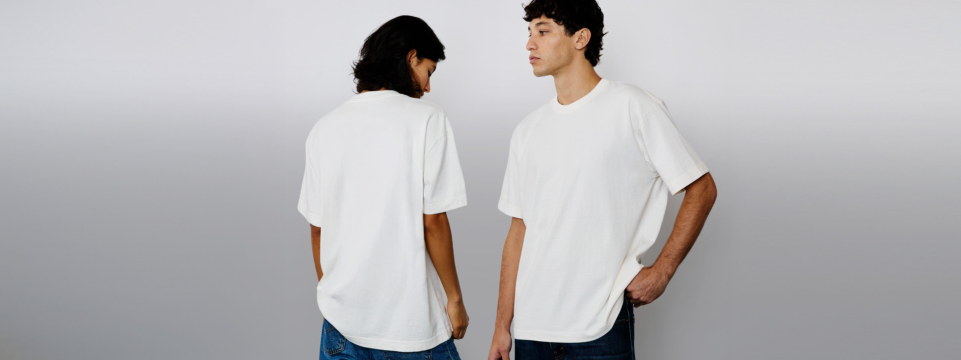 Modelo feminino e modelo masculino vestindo a camiseta heavy oversized off white Kiji, em foto ampla ela de costas e ele de frente.