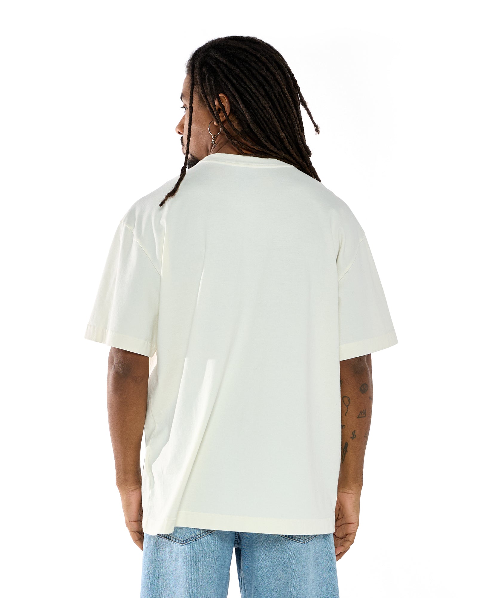 Modelo vestindo a t-shirt oversized na cor off white, vista de costas