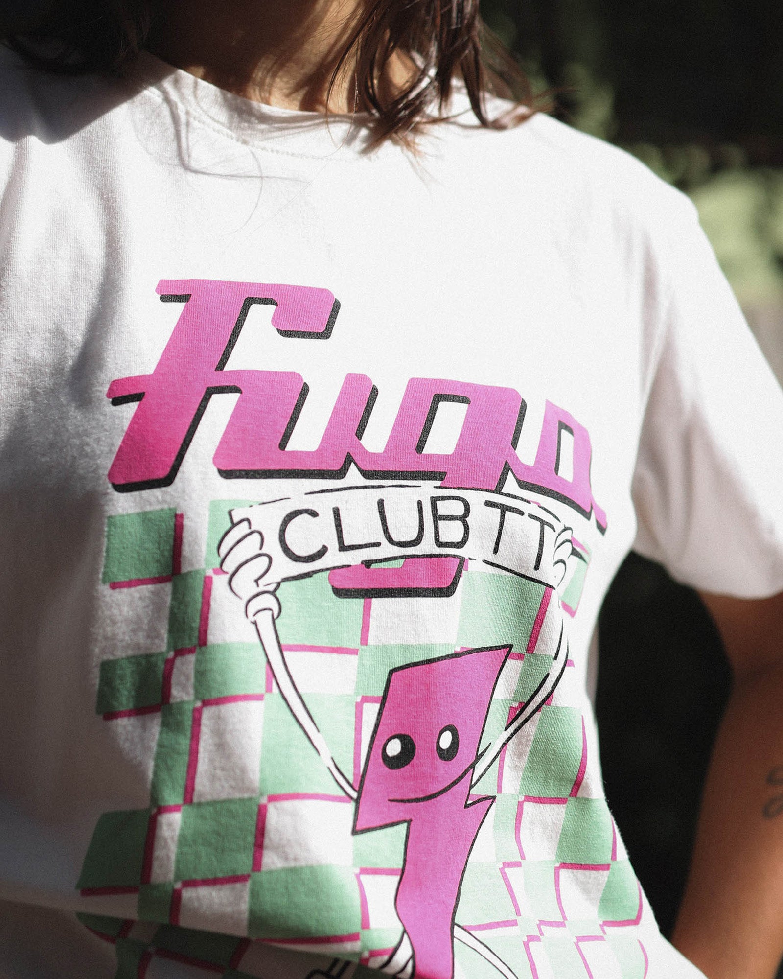 Foto de detalhe da Modelo vestindo a T-Shirt Classic Kiji Off-White TT23, evidenciando os traços de cartoon e desenho a mão livre da estampa, além da cor vibrante dos detalhes em rosa.