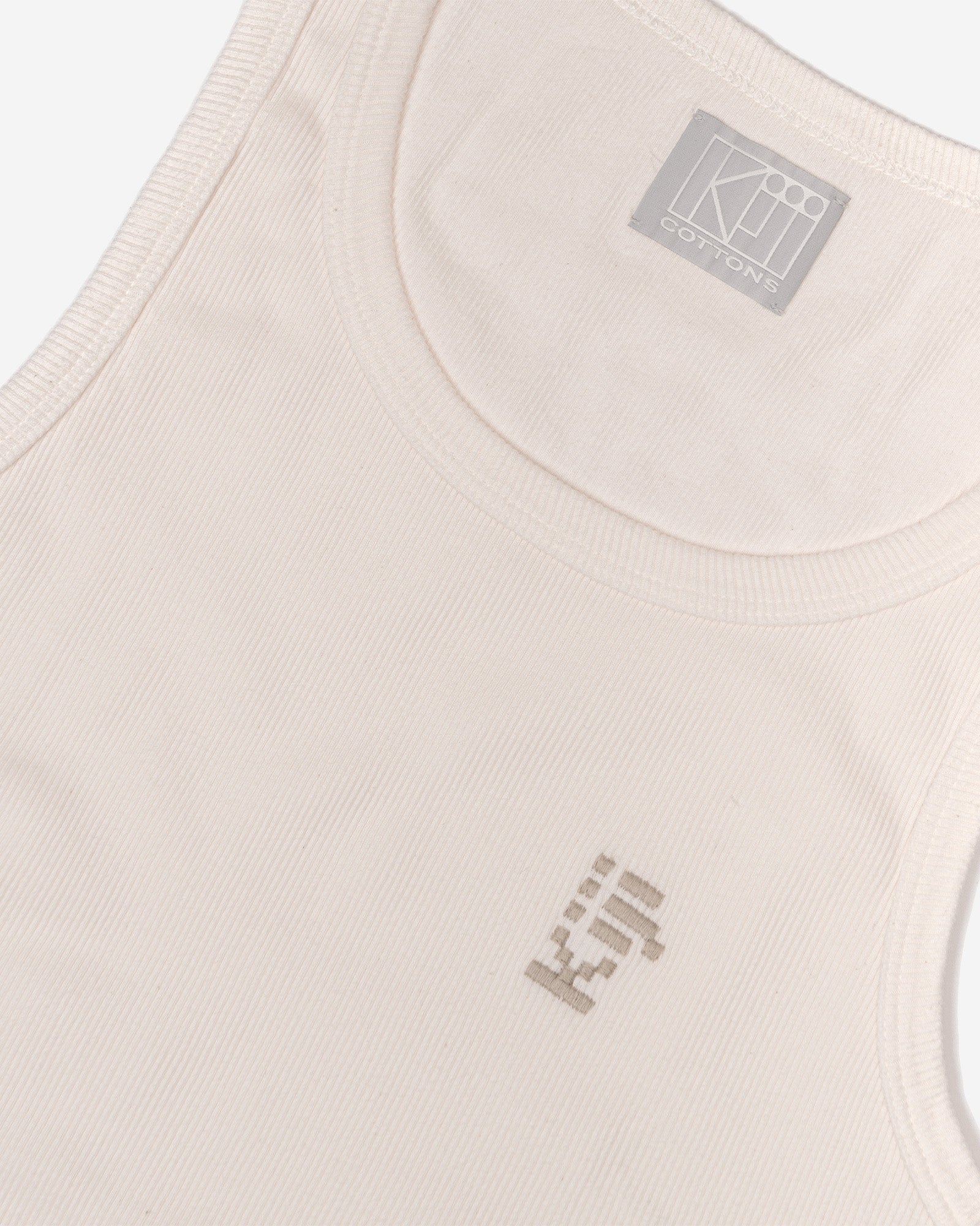 Detalhe da Regata Tank-Top Kiji Off-White mostrando o bordado em alta definição da Kiji, localizado no lado esquerdo do peito.