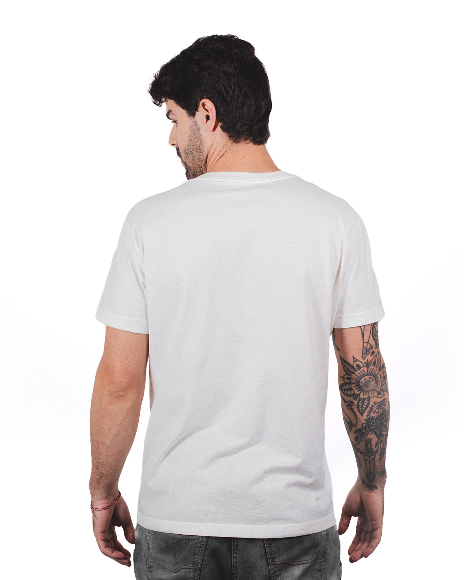 Modelo vestindo a camiseta clássica Kiji na cor off white. Detalhe para as costas e o ajuste da manga.