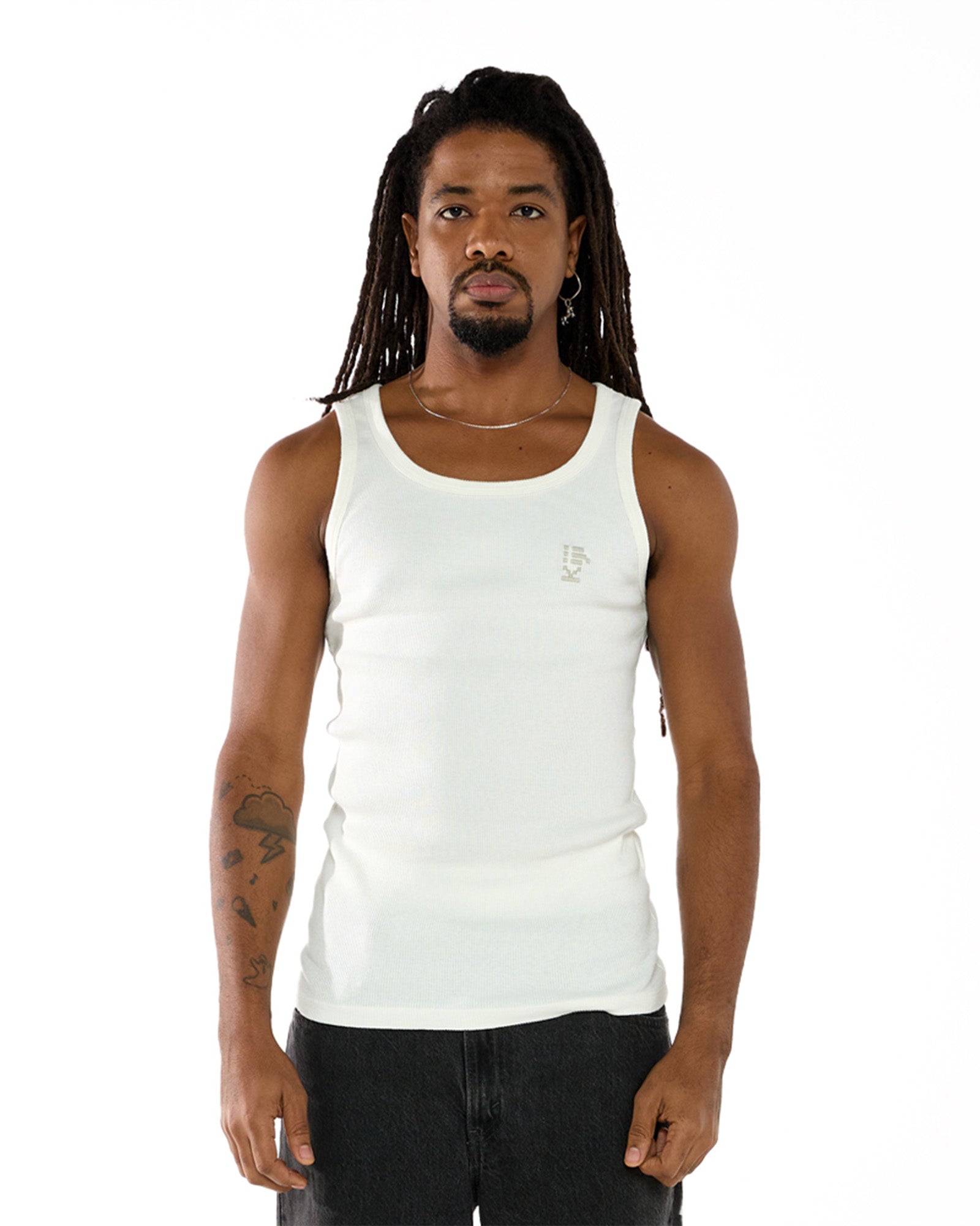 Modelo Negro, de Dreads e calça preta, vestindo a regata canelada Tank-Top Kiji na cor Branca