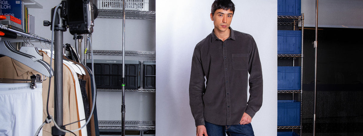 Modelo vestindo camisa de botão Kiji velvet, na cor preto, fundo branco no escritorio Kiji Studio.