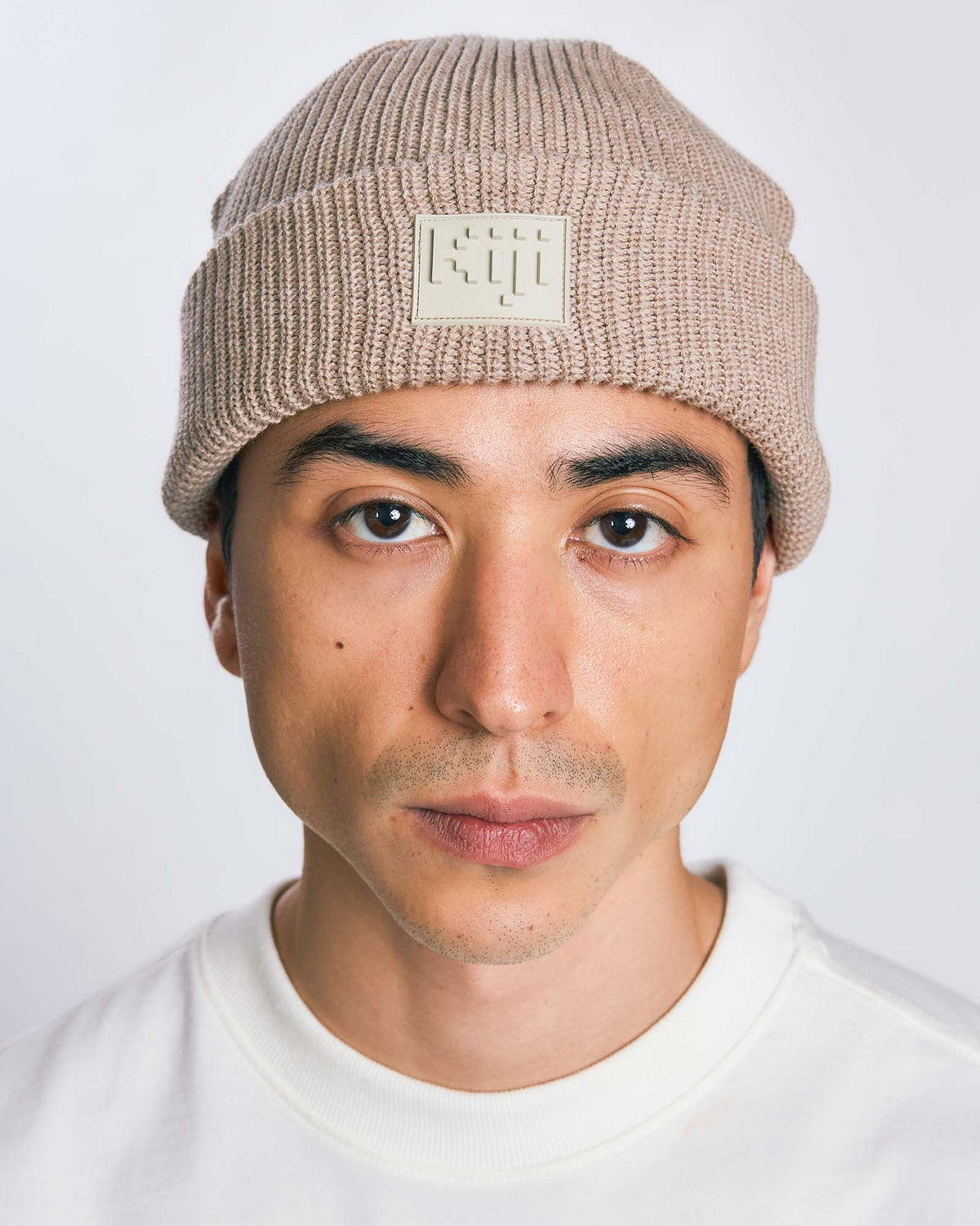 Modelo vestindo Gorro 8bit Kiji de frente, com patch frontal centralizado, na cor fossil.