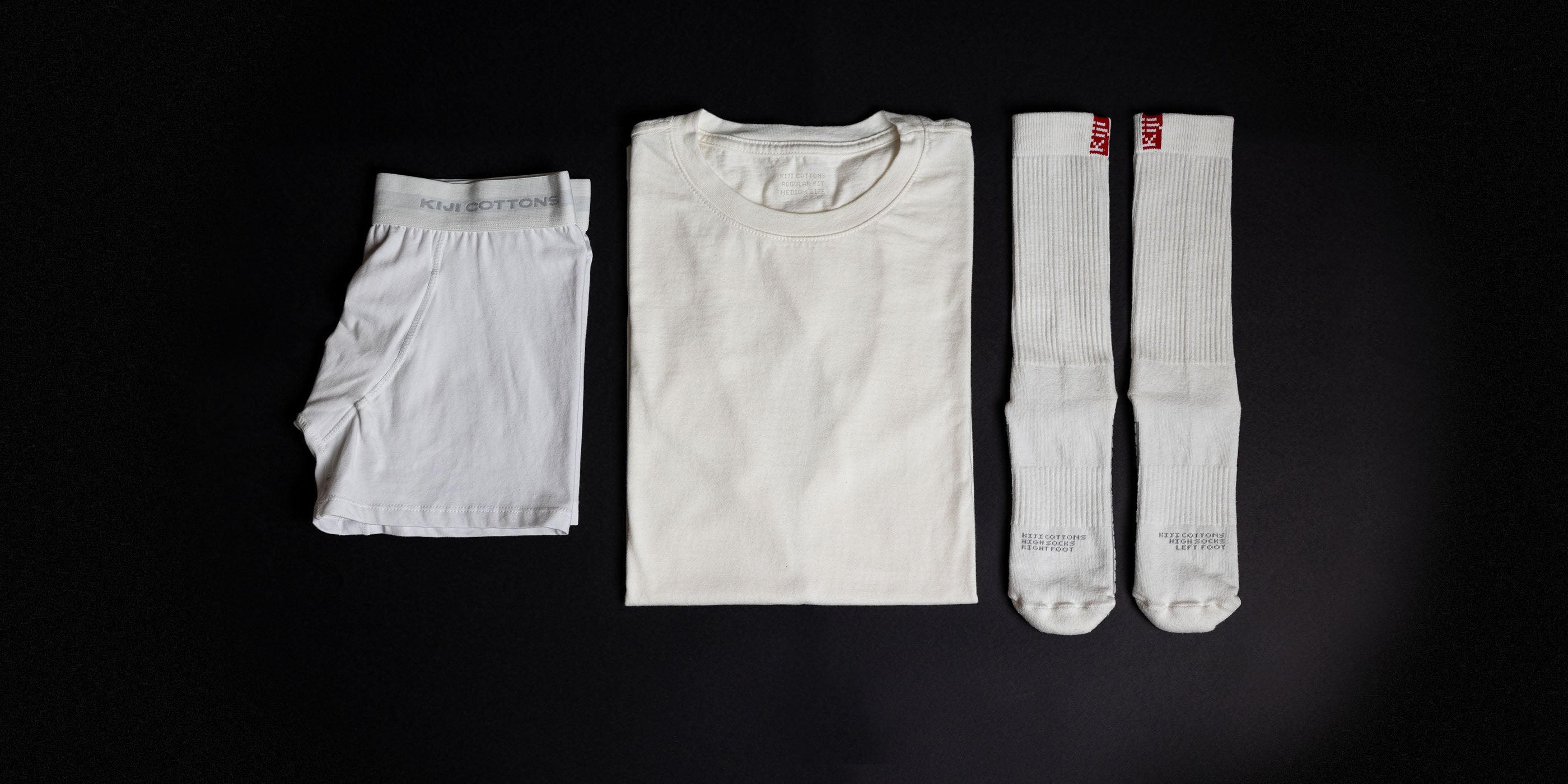 Foto do Trio de Essenciais do Cotidiano: uma cueca boxer kiji branca, uma t-shirt classic kiji off white e uma meia de algodão cano alto kiji flag branca